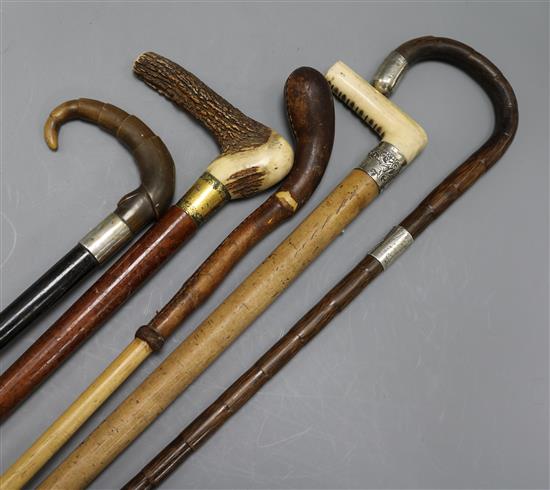 A collection of five walking sticks including three silver mounted